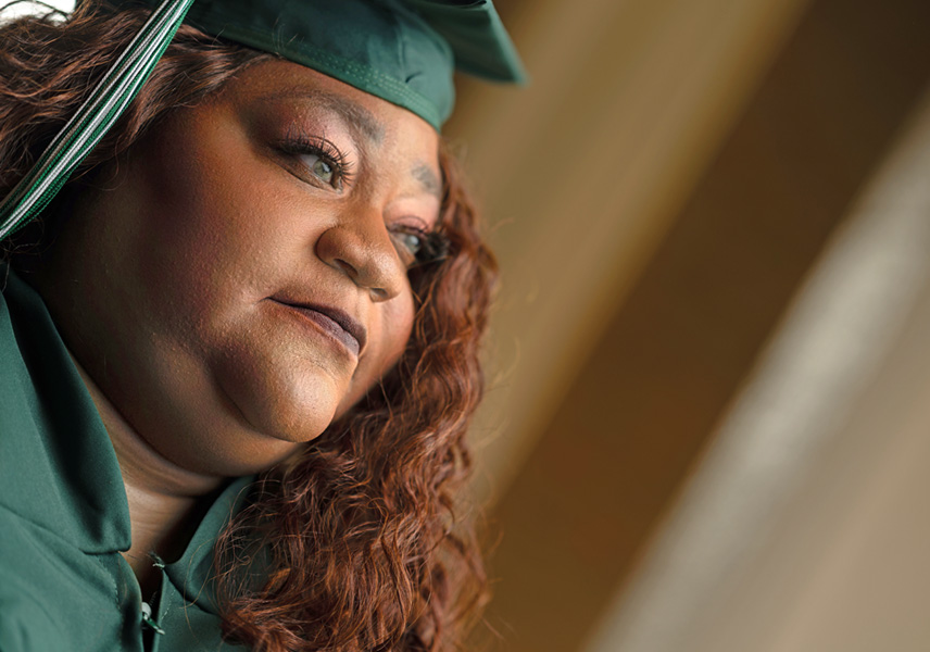 A close up image of Ebony Boatman's face, the camera is looking up and from the side. She's wearing her O C C cap and gown