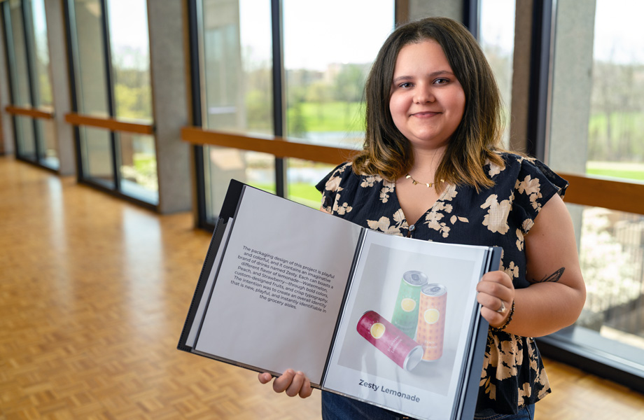 Lizelle Hees posing indoors while holding a book open towards the camera