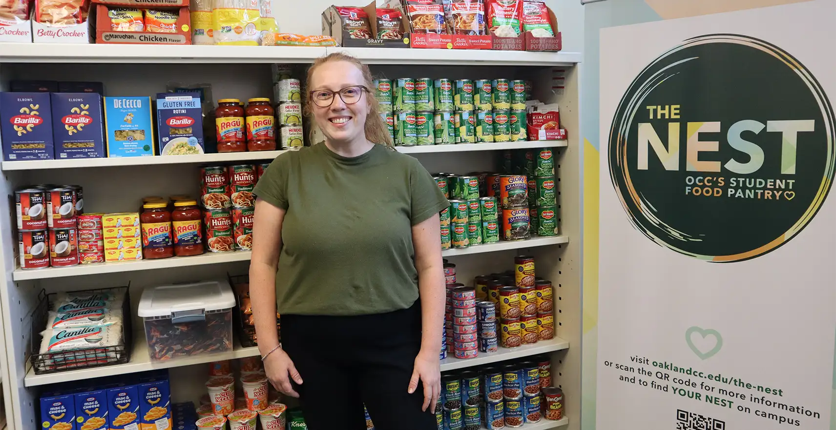 Charlotte Rapids, Food Pantry Associate, stands in front of The Nest Student Food Pantry at the Royal Oak campus.