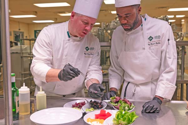 Chef Doug Ganhs to the left of an OCC culinary student.