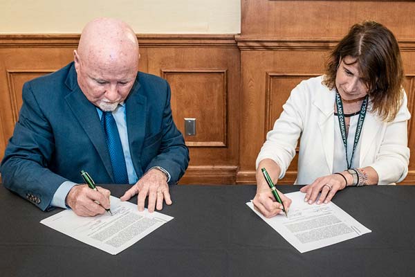 Kevin Corcoran, Ph.D., left, Senior Advisor to the Provost of Oakland University and Jennifer Berne, Ph.D., Provost at Oakland Community College sign the newest agreement between the two schools.