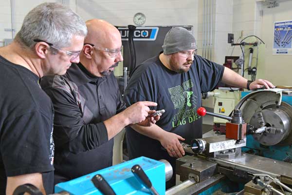 Three men around some heavy machinery.