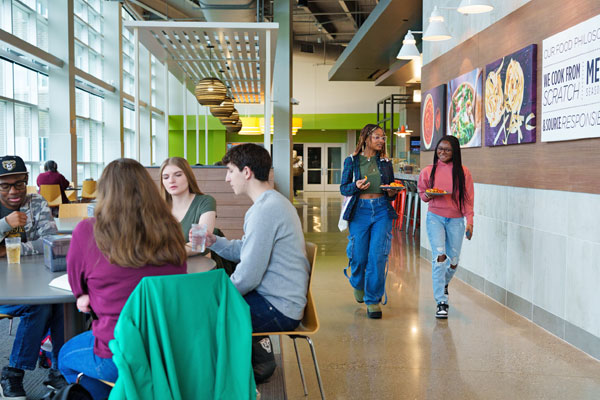 Two students walking and talking in a dining hall
