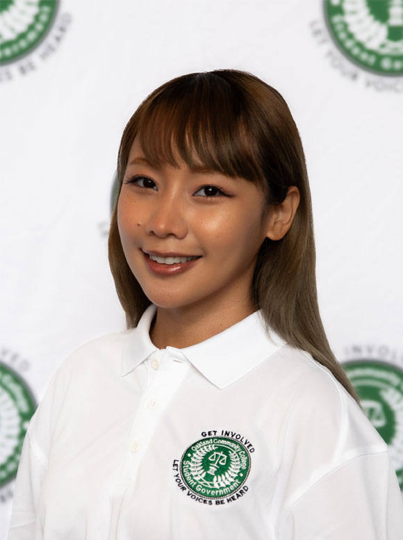 Portrait of a woman in a white polo shirt with a student government logo.